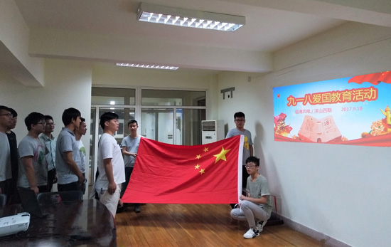 中交三航局临港风电项目部和洋山四期项目部共同开展了爱国教育观影活动，图为员工面向国旗一同齐唱国歌，激情昂扬的进行曲点燃了在场每一位员工的爱国情